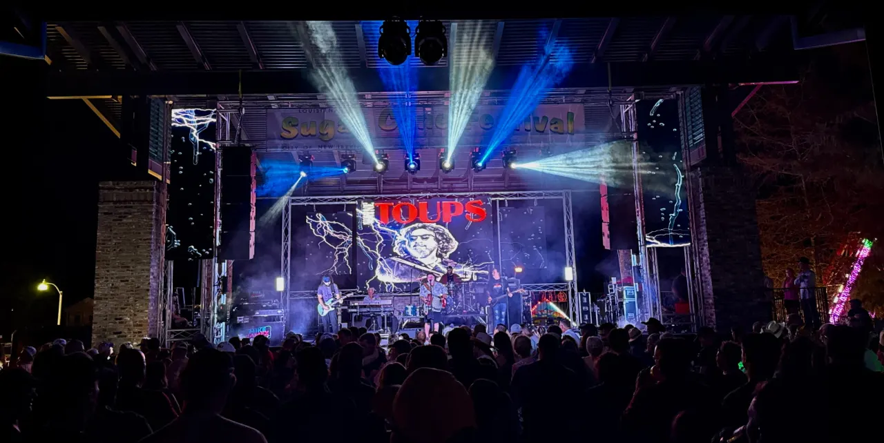 Outdoor Louisiana festival stage with a large LED wall, concert lighting, and a crowd